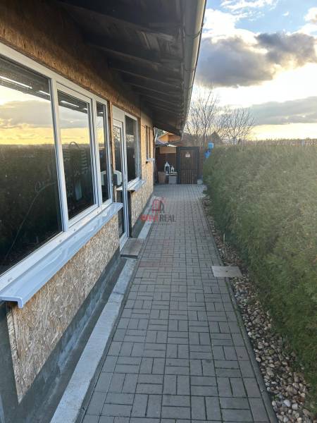 Exteriér gastro prostorů na Devínském jezeře v Bratislavě, s upraveným chodníkem.