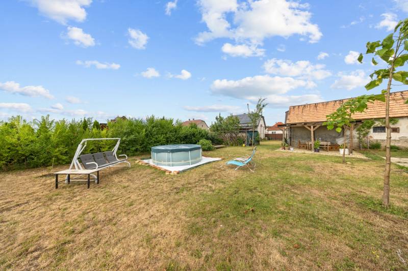 Zahrada rodinného domu v Sološnici na ulici Hoštáky s bazénem a houpačkou.