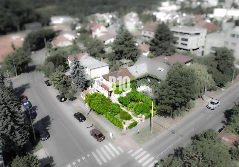 Rodinný dům v lokalitě Bratislava - Staré Město, obklopený zelení a cestou s auty.