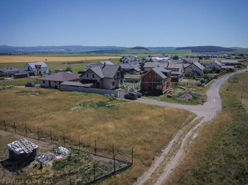 Pozemky pro bydlení v Mlynici s rodinnými domy a venkovskou krajinou v pozadí.
