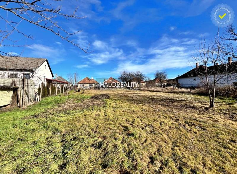 Pozemek k bydlení ve Velkých Ludincích se sousedícími domy a travnatou plochou.