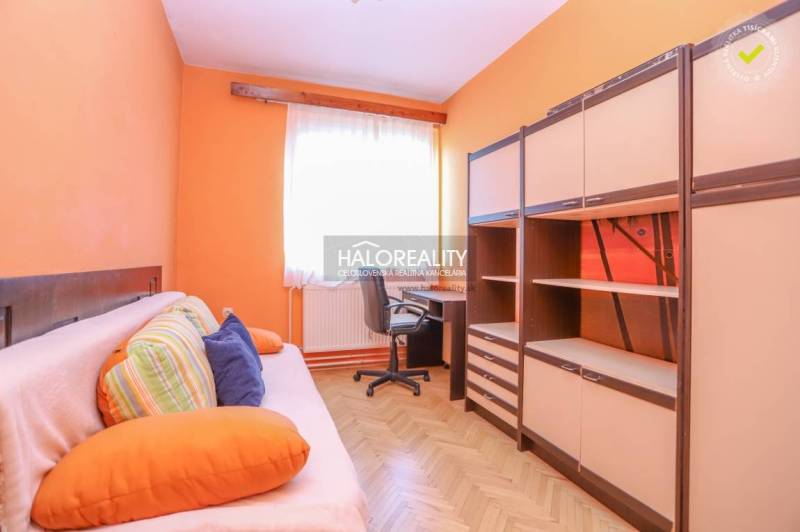 Pokoj v 3-pokojovém bytě s oranžovými stěnami, sedačkou, stolem a skříněmi.