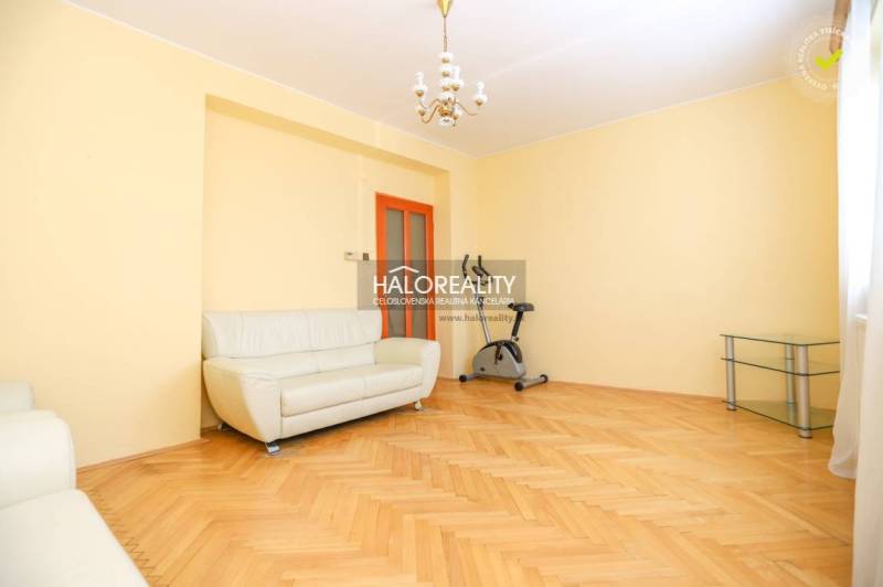 Světlý obývací pokoj v 3-pokojovém bytě s pohovkou a cvičebním kolem.