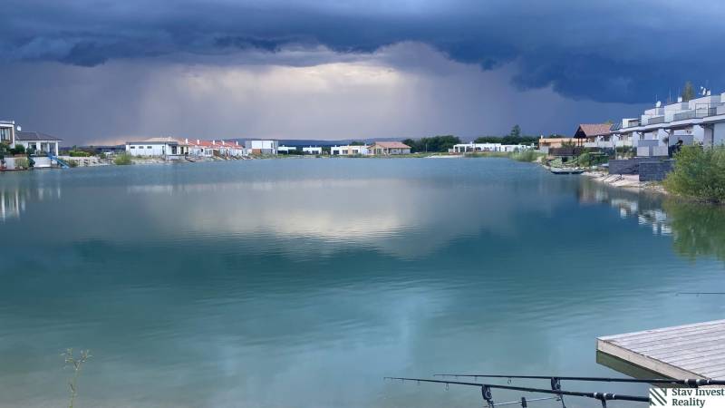 Jezero obklopené domy v Boldogu, pozemky - bydlení, dramatická obloha před bouří.