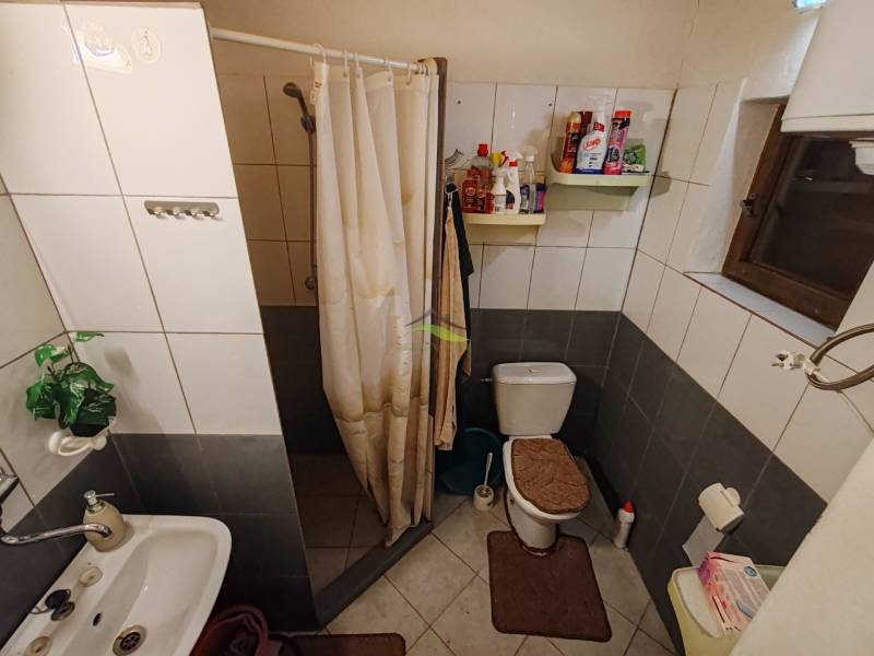 Koupelna v chatě s WC, sprchovým koutem a bílými dlaždicemi.