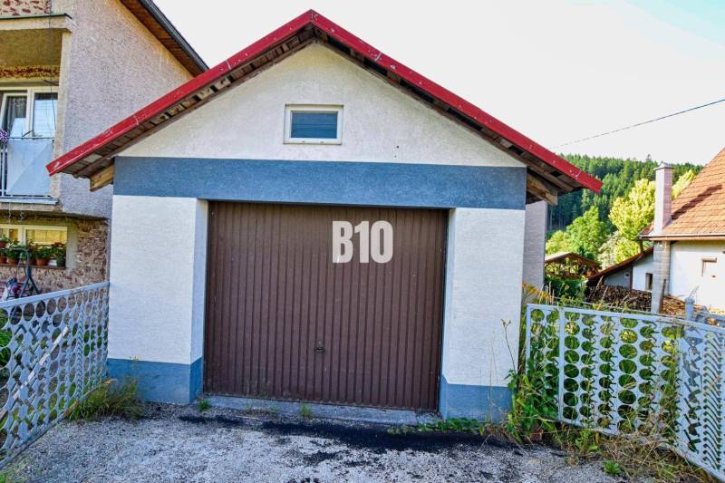 Garáž u rodinného domu v Turzovce, obklopená zelení a plotem.