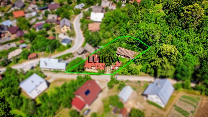 Letecký pohled na rodinný dům v Púchově obklopený zelenými zahradami a ulicí.