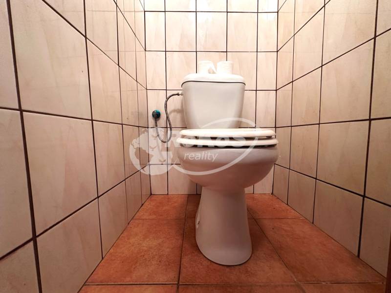 Toaleta v 3-pokojovém bytě s dlažbou na stěnách i podlaze.