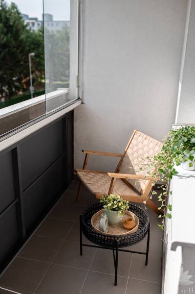 Balkon 2-pokojového bytu s křeslem, stolkem a rostlinami.