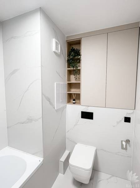 Minimalistická koupelna v 2-pokojovém bytě s WC, vanou a úložnými prostory.