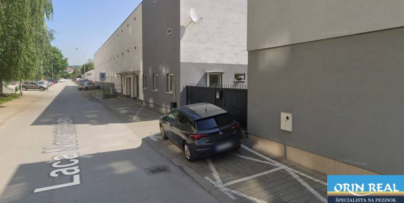 Auto parkující u budovy na ulici Laca Novomeského v Pezinku, u garáží.