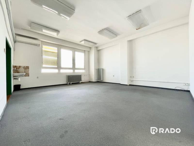 Prostorné kanceláře s umyvadlem, velkými okny a radiátorem.
