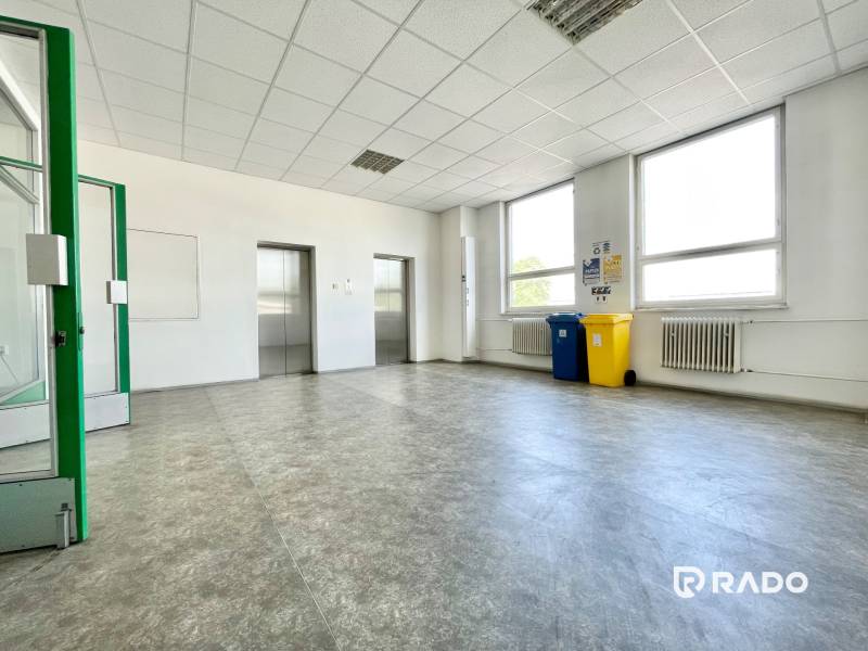 Kanceláře s výtahy, recyklačními koši a radiátory, světlý prostor.
