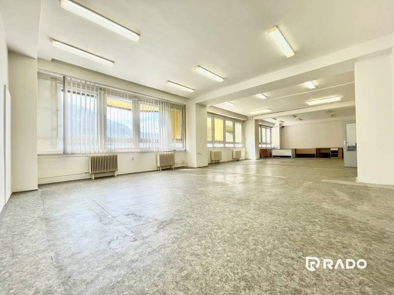 Prostorné kanceláře s velkými okny a linoleovou podlahou.