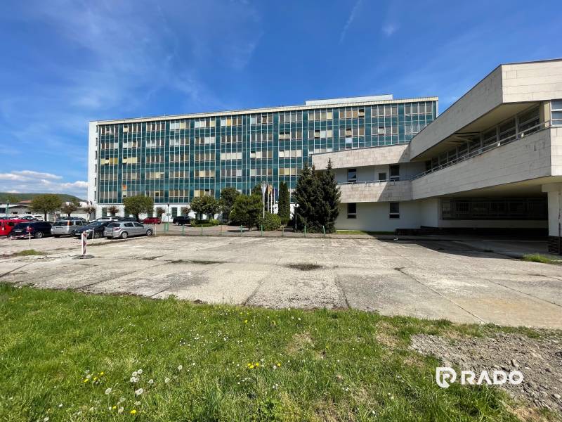 Budova kanceláří na ulici K výstavišti ve městě Trenčín s parkovištěm a zelení.