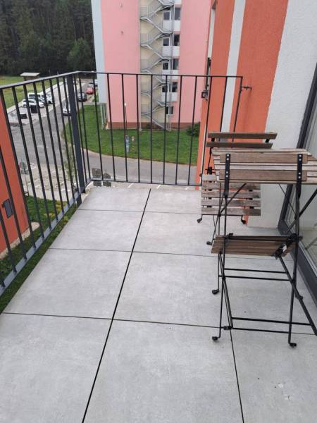 Balkón s výhledem na ulici Jilemnického ve městě Svit; obsahuje dřevěný nábytek.