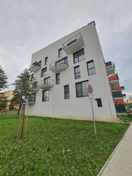Bytový dům na Jilemnického ulici ve Svitu, obklopený zelení a chodníkem.