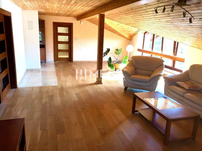 Podkrovní obývací prostor s dřevěnou podlahou a sedací soupravou ve 3-pokojovém bytě.