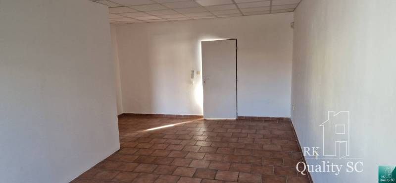 Interiér budovy s bílými stěnami a dlažbou na podlaze.
