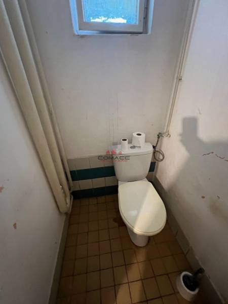 Koupelna s toaletou v rodinném domě, obsahuje okno, dlažbu a toaletní potřeby.