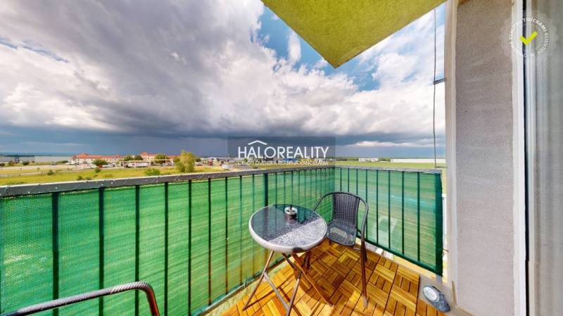 Balkon v garsonce s výhledem na Senec, posezení a oblačné nebe.