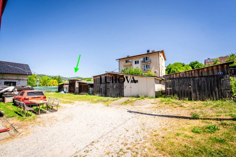 Dvůr s několika dřevěnými budovami a zaparkovaným autem v Púchově, u 2-pokojového bytu.