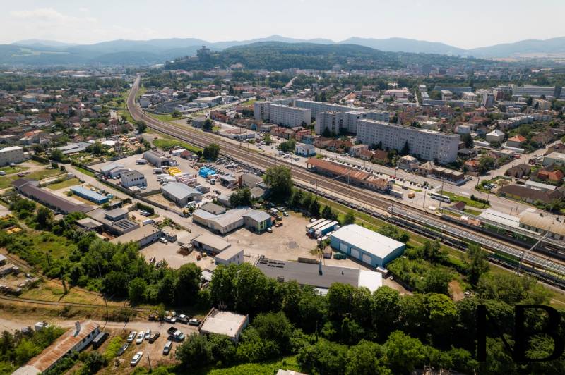 Letecký pohled na Trenčín, Kasárenskou ulici a sklady a haly, v pozadí hory.