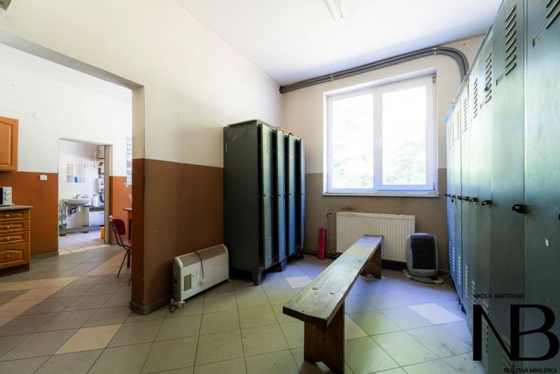 Šatna se skříňkami, lavicí a oknem v interiéru zvláštních nemovitostí.