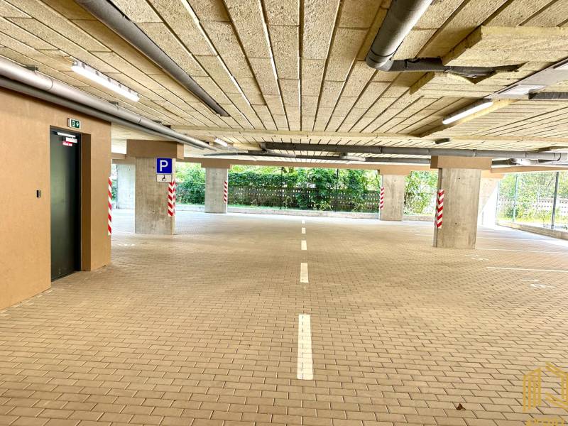 Parkovací garáž s bezbariérovým vstupem, osvětlená a s vyznačenými parkovacími místy.