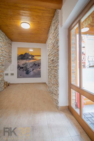 Chodba Rekreačního apartmánu s kamennými obloženými stěnami a obrazem hor.