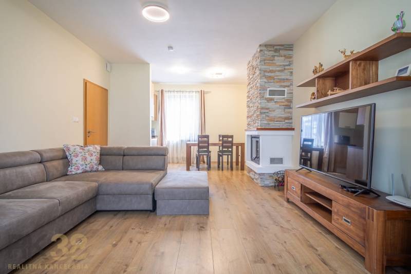 Obývací pokoj v rekreačním apartmánu s krbem a pohodlnou sedačkou.