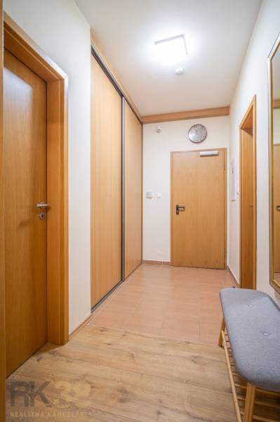 Chodba s dřevěnými dveřmi a úložným prostorem v rekreačním apartmánu.