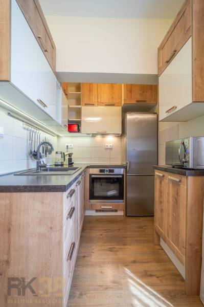 Kuchyně v rekreačním apartmánu s dřevěnou podlahou a moderním vybavením.