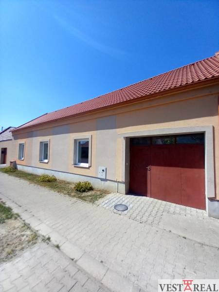 Rodinný dům v Trakovicích se šikmou střechou a dvěma okny směřujícími na ulici.