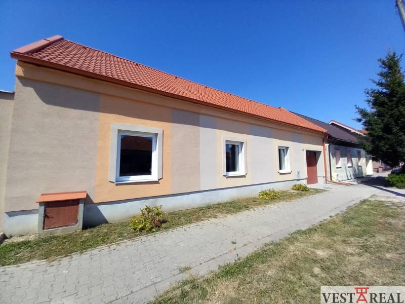 Rodinný dům v Trakovicích s oranžovou fasádou a červenou střechou.