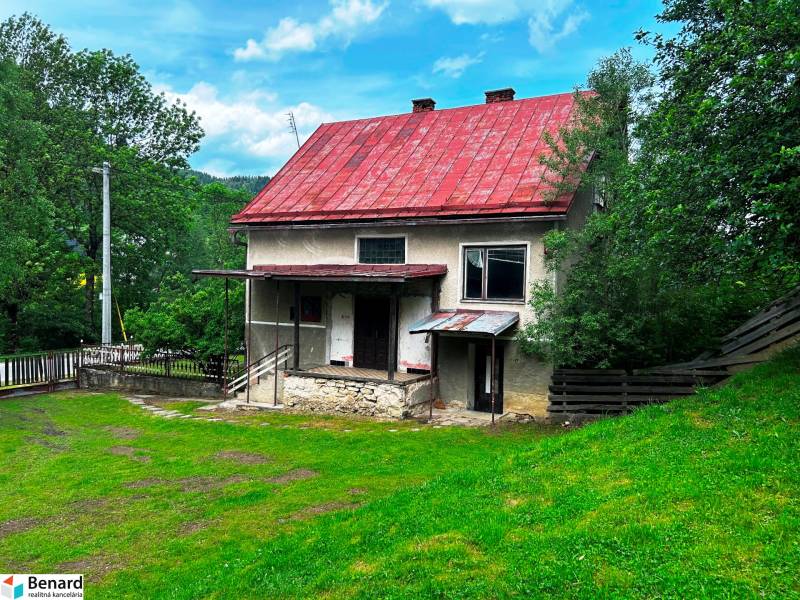 Rodinný dům ve Velké Lesné s červenou střechou a zahradou obklopenou zelení.