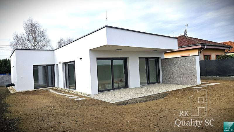 Rodinný dům v Tureni s rovnou střechou a velkými skleněnými dveřmi.