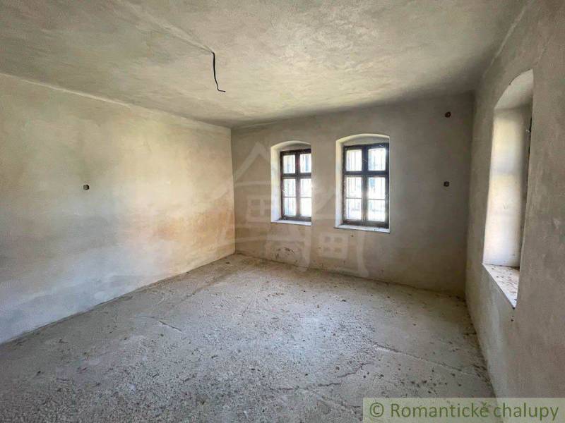 Prázdná místnost se dvěma okny v rodinném domě.