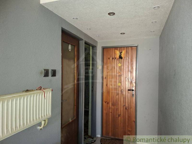 Vstupní chodba v rodinném domě s dřevěnými dveřmi a radiátorem.