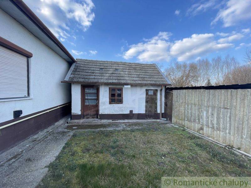 Exteriér rodinného domu v Nových Zámkoch s vedlejší přístavbou a oplocením.