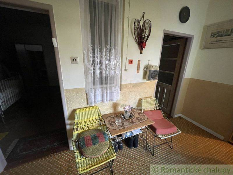 Dvě pletené židle a stolek s květinami v rodinném domě, interiér.