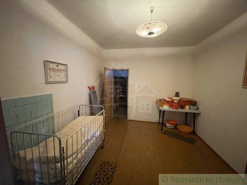 Interiér rodinného domu s dětskou postýlkou, posezením a nostalgickou atmosférou.
