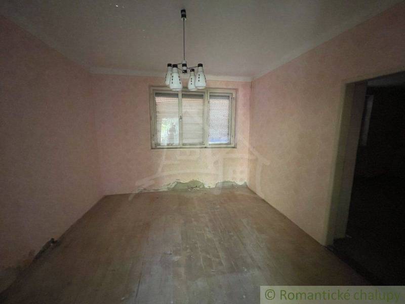 Prázdná místnost s dřevěnou podlahou, světlem a oknem v rodinném domě.