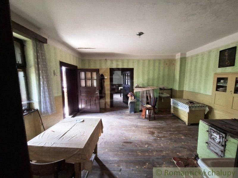 Interiér rodinného domu s dřevěnou podlahou, starožitným nábytkem a jednoduchým stolem.