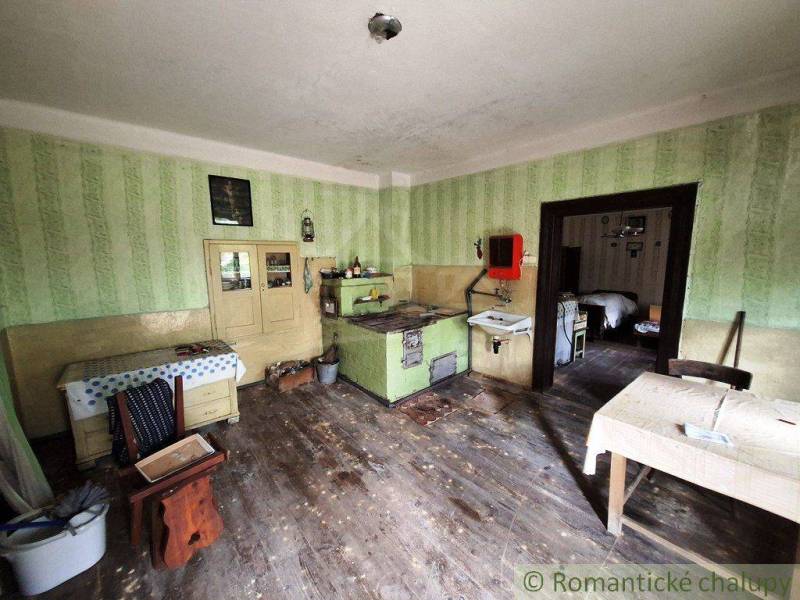 Tradiční kuchyně rodinného domu s kachlovými kamny a dobovým nábytkem.