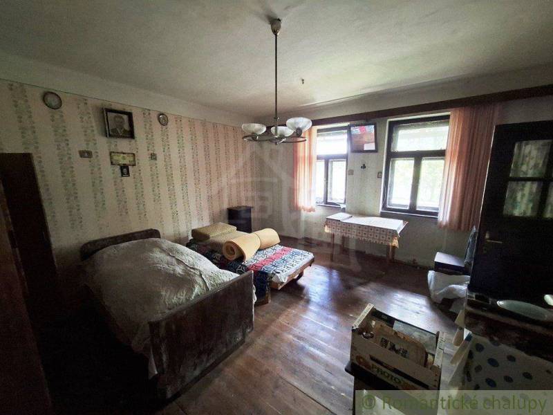 Pokoj v rodinném domě s postelí, dřevěnou podlahou a vzorovanou tapetou.