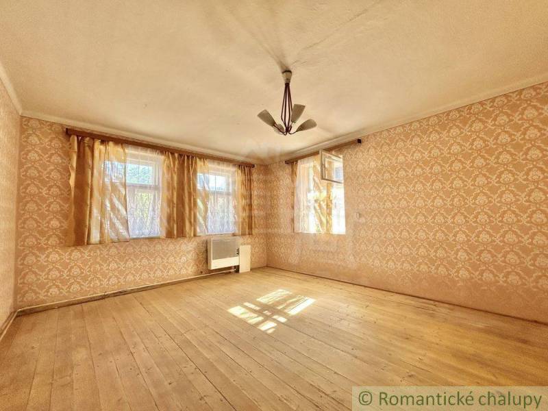 Pokoj v rodinném domě s dřevěnou podlahou a tapetami.