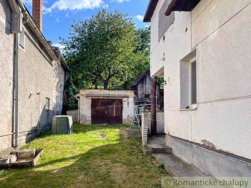 Dvůr rodinného domu v Sielnici s přístřeškem a stromem v pozadí.