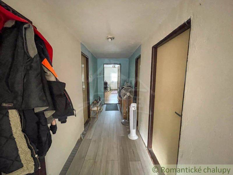 Chodba v rodinném domě s věšáky, podlahou a ventilátory.