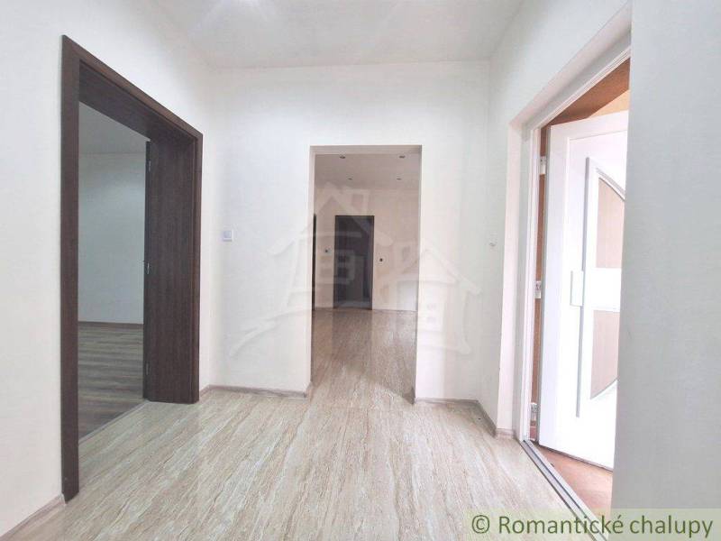 Chodba rodinného domu s laminátovou podlahou a bílými stěnami.